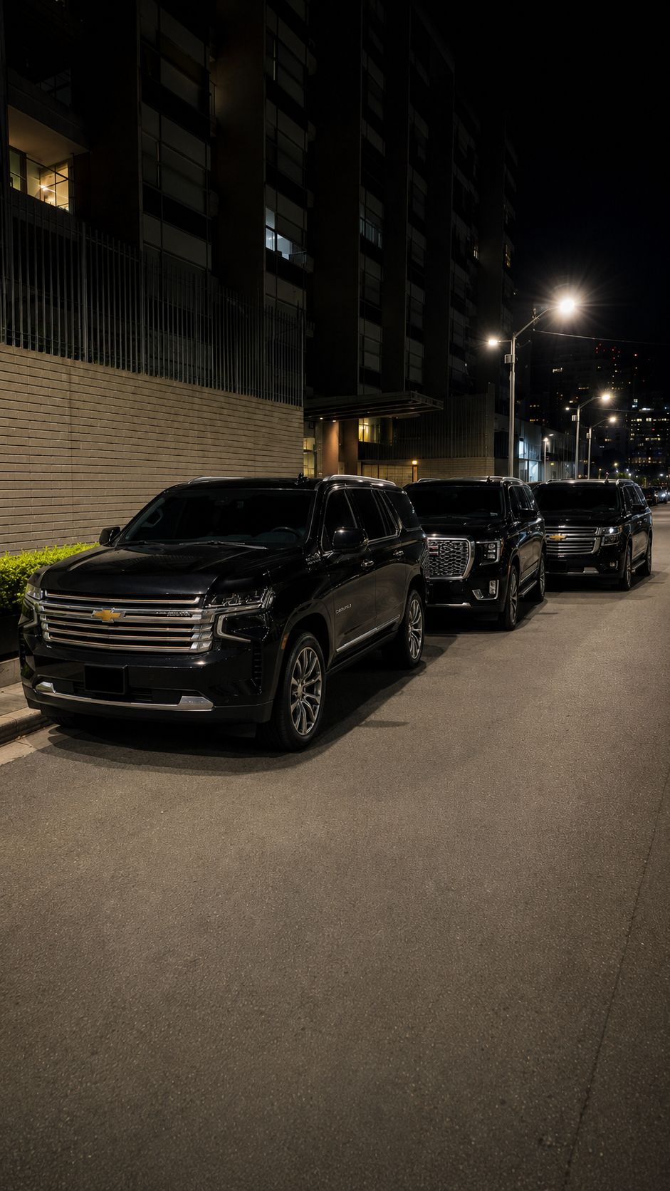 Tres SUV negras estacionadas en fila durante una escena nocturna.