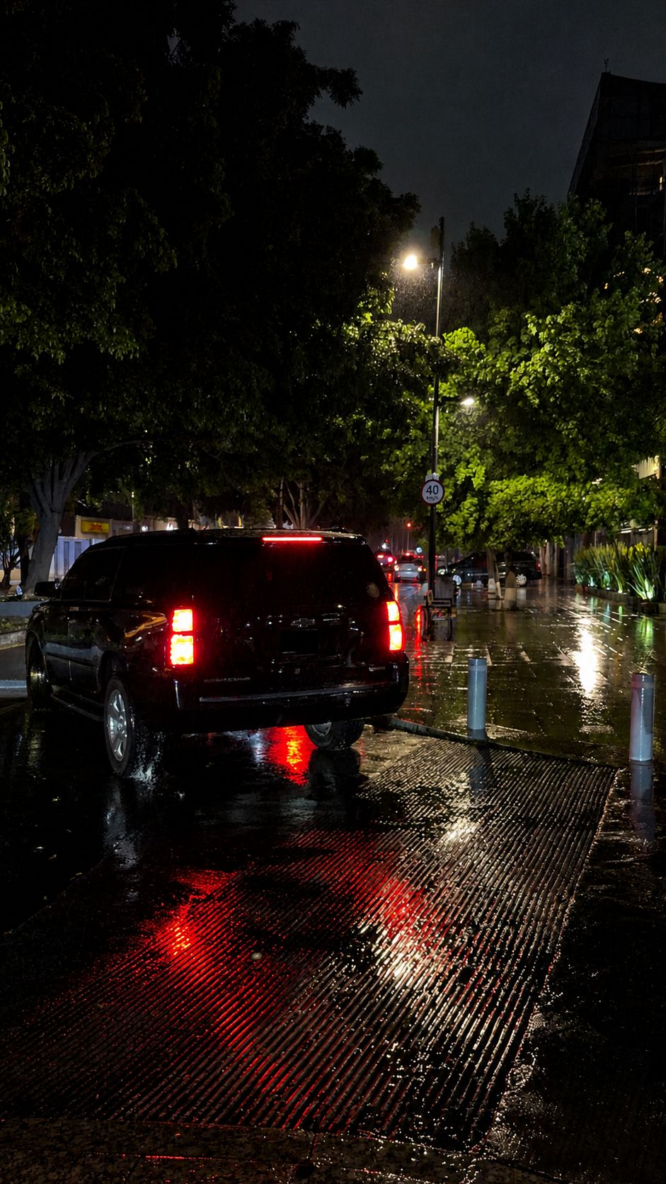 SUV negra vista desde atrás durante un trayecto nocturno bajo la lluvia.